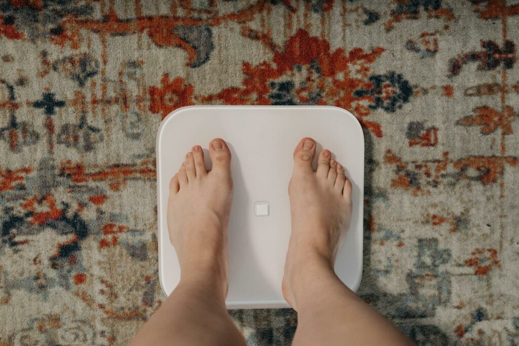 Overhead view of feet on a smart scale atop a decorative carpet, focusing on balance and health.